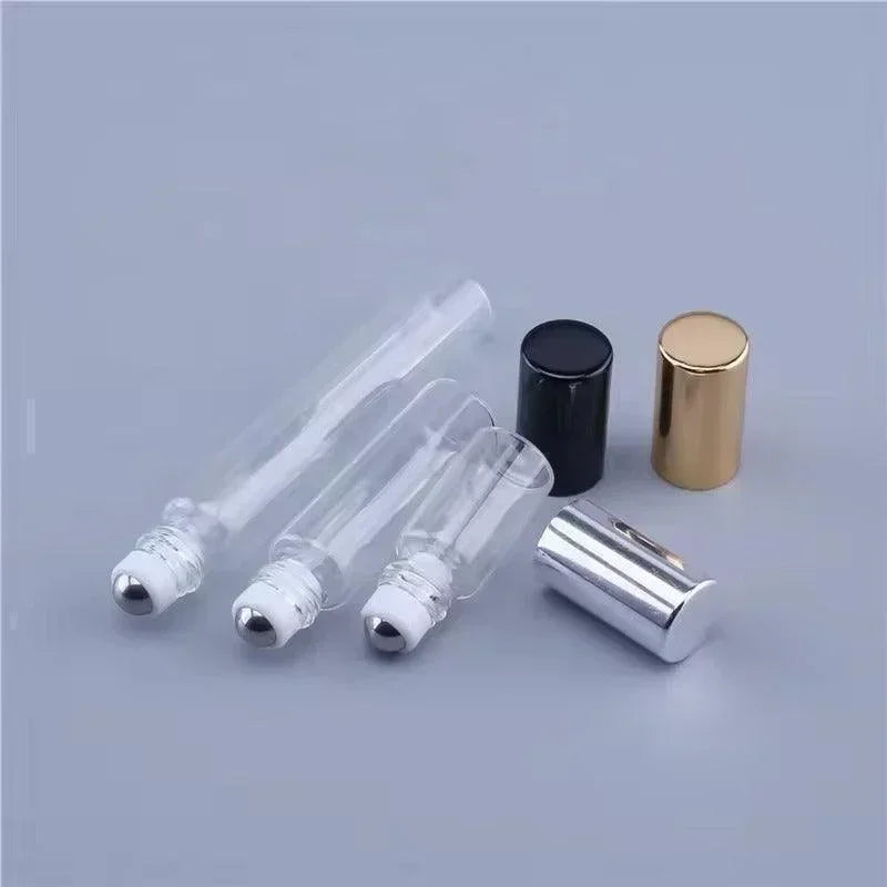 Clear glass roll-on bottles for cosmetics with silver, black, and gold caps on grey background