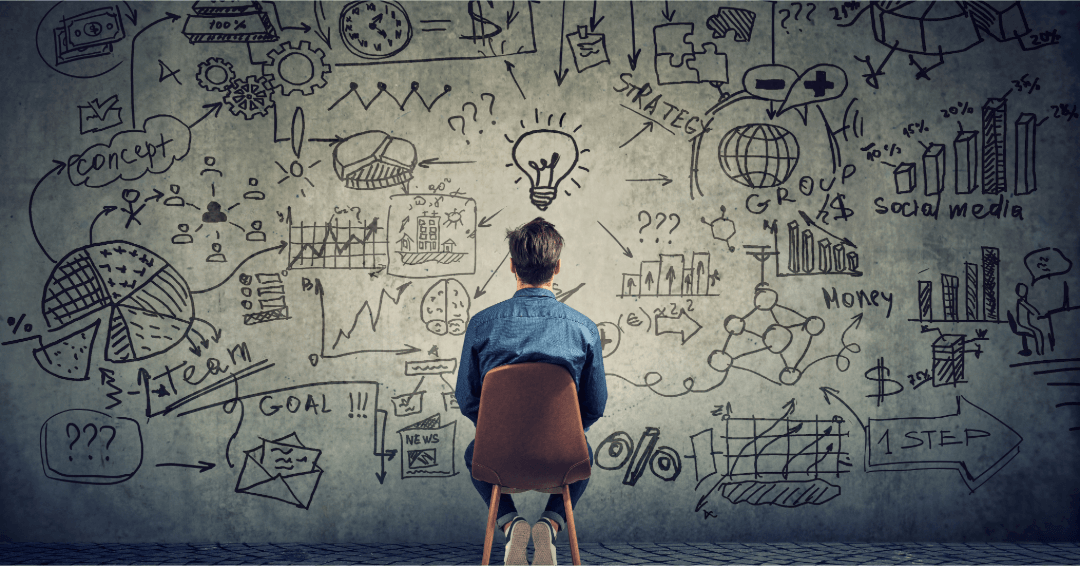 Person brainstorming with business strategy charts, graphs, and marketing doodles on wall