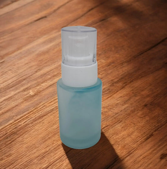 Frosted glass cosmetic pump bottle with white dispenser on wooden surface