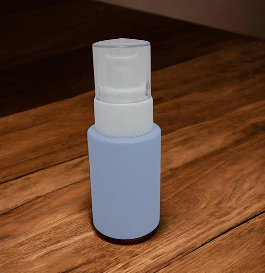 Frosted cosmetic glass pump bottle with light blue coating on wooden surface