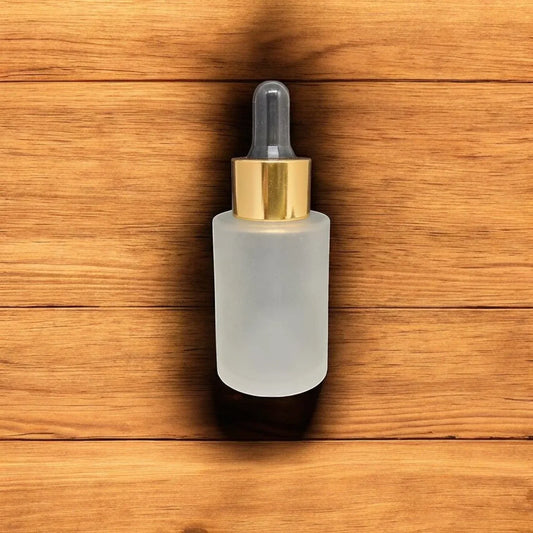 Frosted glass dropper bottle with gold cap for cosmetic packaging on wooden background